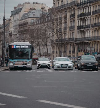 A bustling Paris street with cars and historic buildings on a cloudy day.