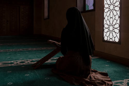 Back View of a Woman Sitting in a Mosque and Praying 