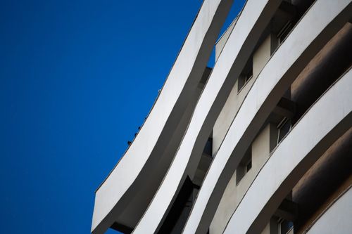 Free Curved modern building façade contrasting strikingly against a deep blue sky in an urban setting. Stock Photo