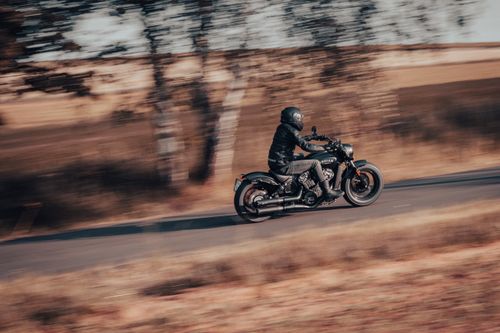 Free Motorcyclist on a panning shot capturing speed and motion on a tranquil countryside road. Stock Photo