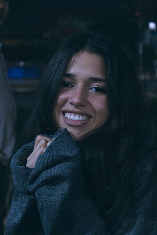 Free Happy woman with long hair wearing a sweater, smiling warmly at night. Stock Photo