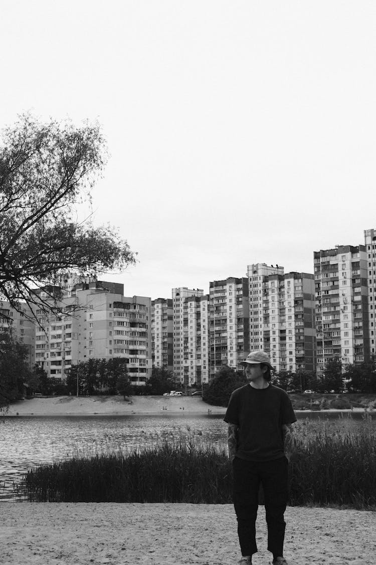 Man In A Hat Posing In Urban Landscape With A Pond