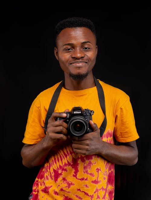 Man in an Orange Shirt Holding a Camera