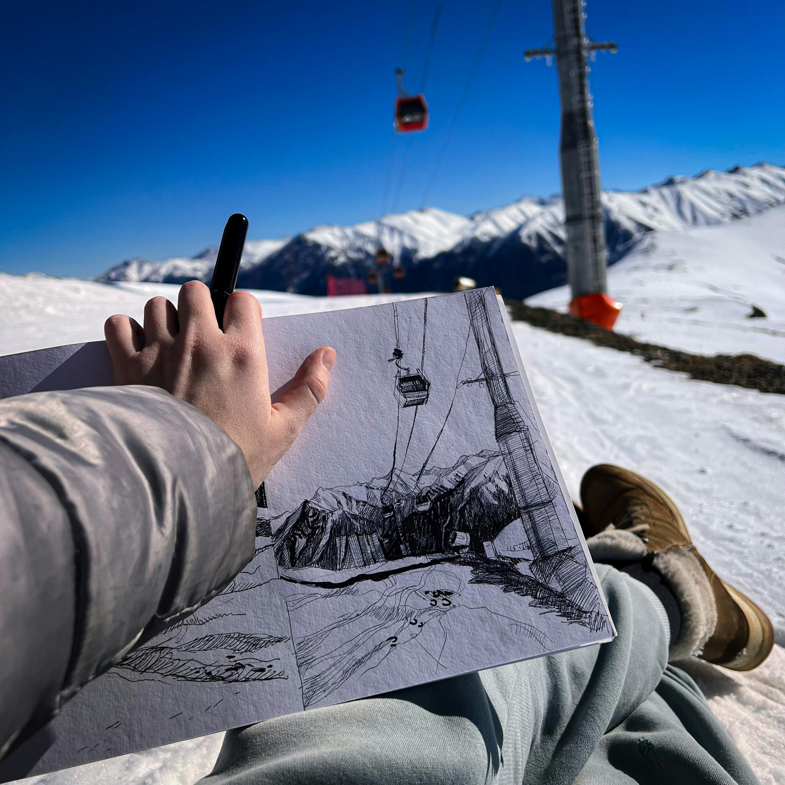 Man Sitting on a Ski Slope and Sketching 