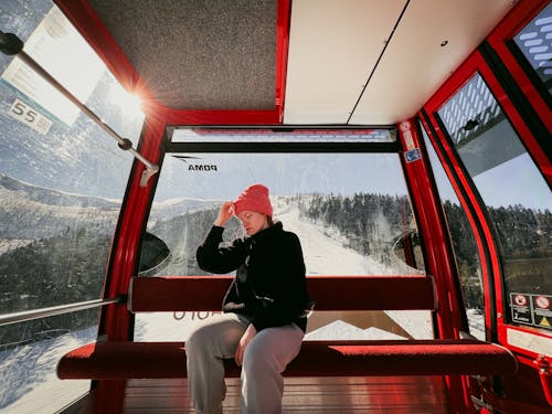 Woman Sitting inside a Ski Lift above a Ski Slope 