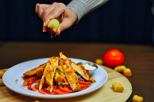 A Person Squeezing a Lime over Chicken Salad