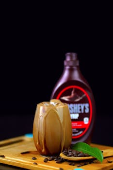 Refreshingly cool chocolate iced coffee with coffee beans and syrup, perfect for a sweet indulgence.