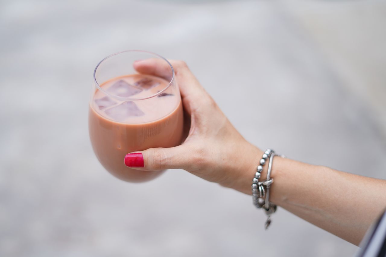 close up of a woman s hand holding a glass of iced coffee with bracele