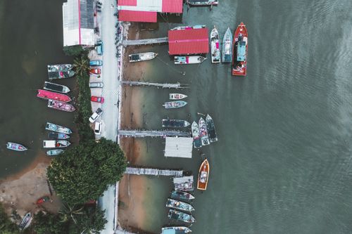 Free High-angle view of a marina with colorful boats docked along a vibrant shoreline. Stock Photo