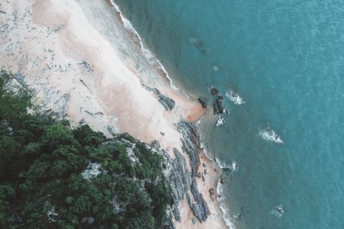 Free A breathtaking aerial image capturing a secluded beach with lush greenery and turquoise water. Stock Photo