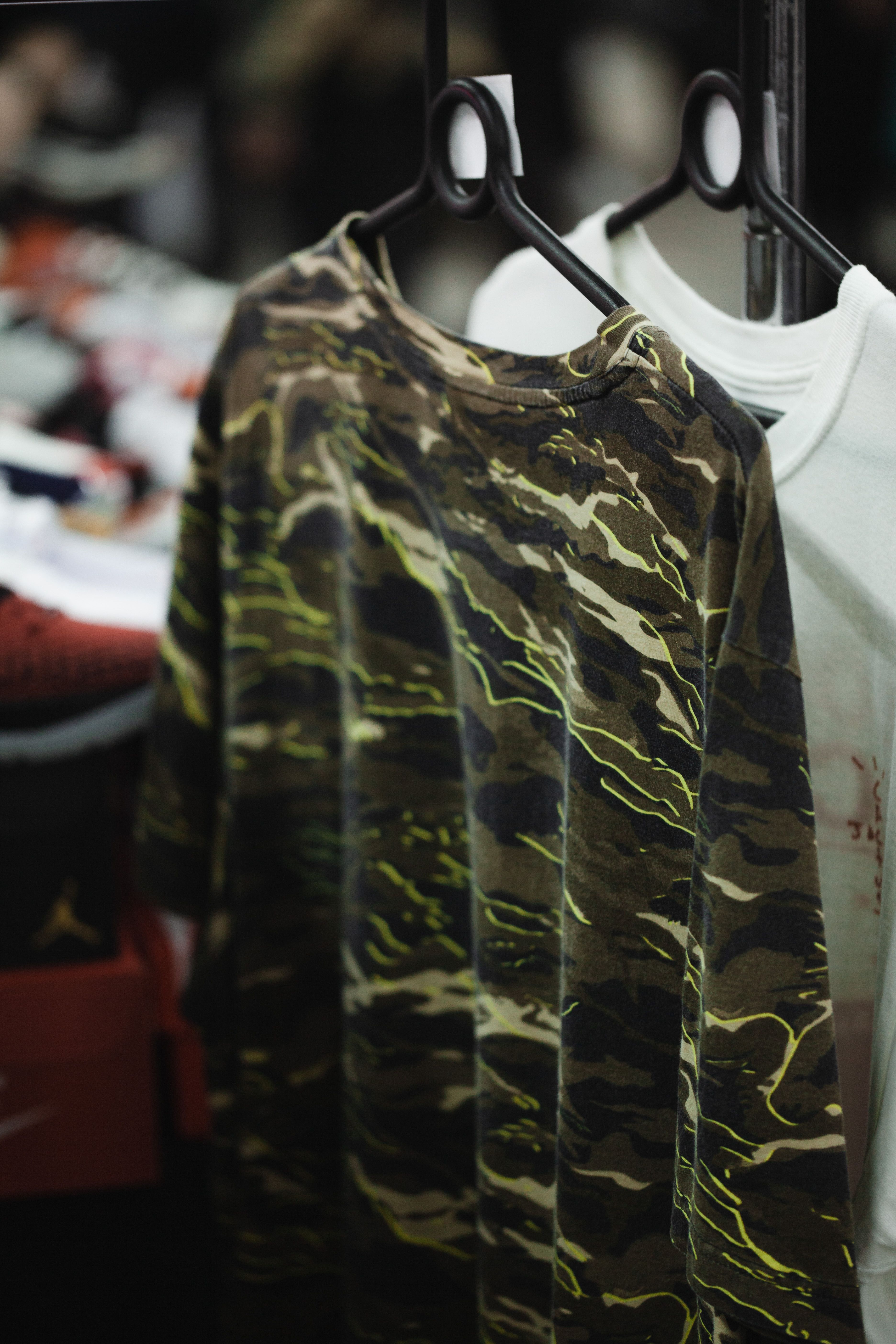 Close-up of a camouflage T-shirt on a hanger in a retail setting.