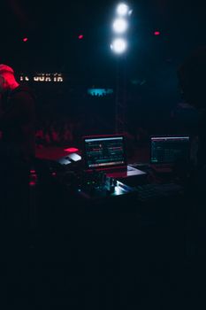 An energized DJ setup with computers and consoles in a lively nightclub. Ideal for electronic music themes.