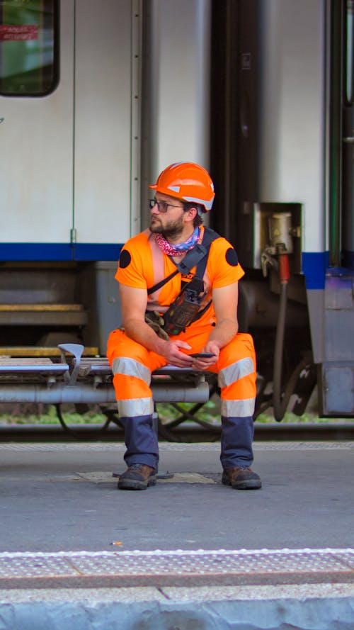 Free Man in Orange Safety Helmet and Clothes Sitting  Stock Photo