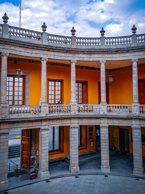 Free Stunning view of a historic courtyard with bright orange walls and classic columns in Mexico City. Stock Photo