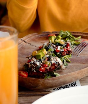 Fresh vegetable salad with avocado and tomato served on a wooden plate.