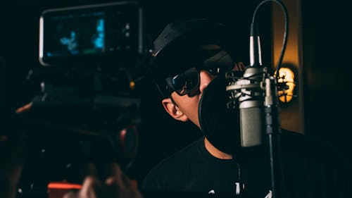 Free Man in Black Cap and Black Framed Sunglasses in Front Recording Microphone Stock Photo