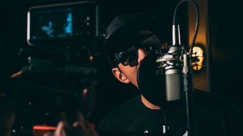 Free A hip-hop artist records vocals in a dark, atmospheric studio setting. Stock Photo