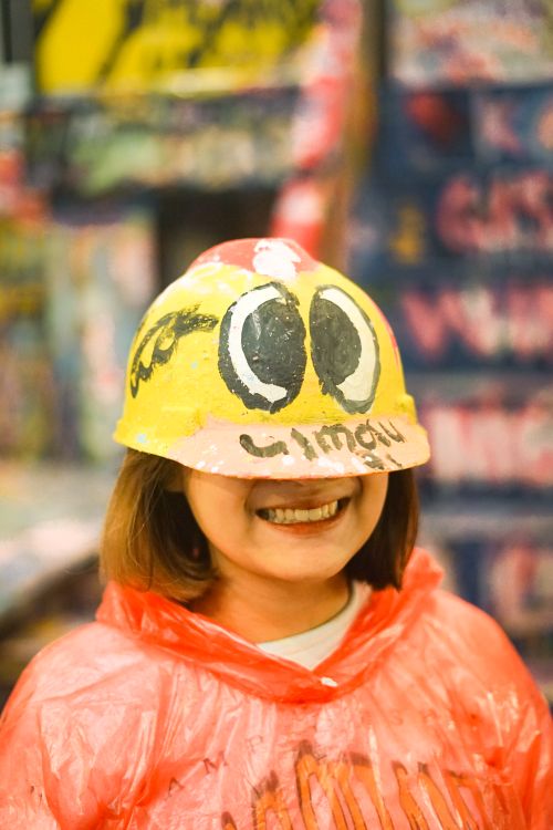 Free A woman smiling while wearing a creatively painted hardhat, indoors. Stock Photo