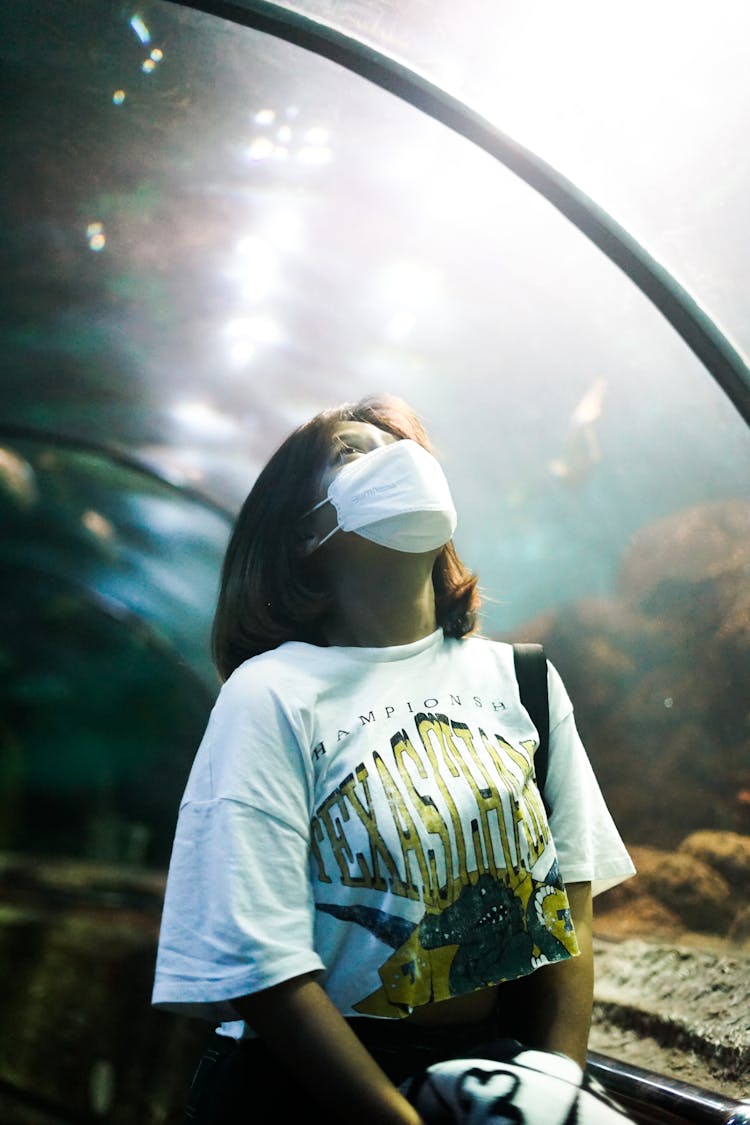 Woman In White Crew Neck T-shirt Standing Under The Glass Aquarium