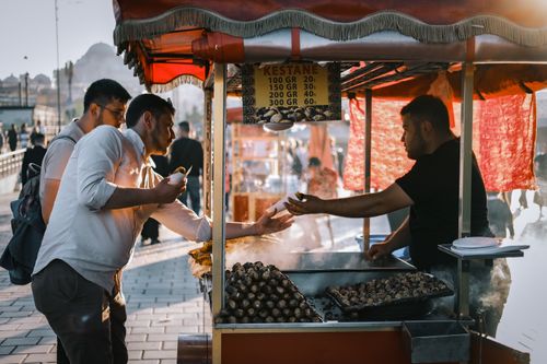 Free A bustling street market scene with people buying roasted chestnuts in İstanbul. Stock Photo