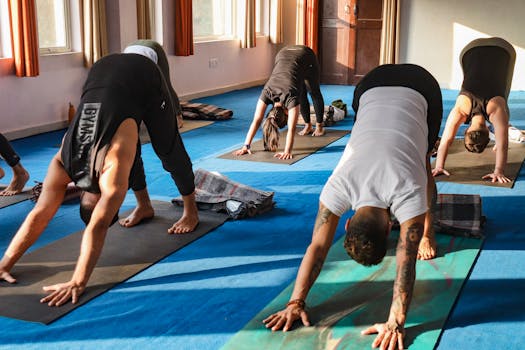 A diverse group practicing yoga in a peaceful studio in Rishikesh, India under warm sunlight.