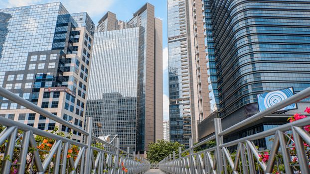 A vibrant cityscape featuring tall skyscrapers and a footbridge adorned with plants, showcasing urban architecture.