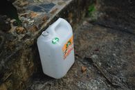 A large white plastic container resting on a textured stone surface outdoors.