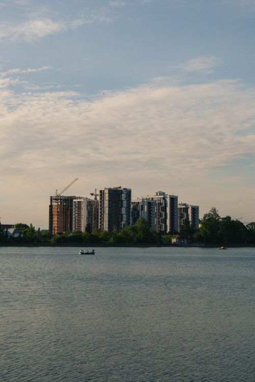 Free Skyline of modern buildings by a tranquil waterfront with boats under a cloudy sky. Stock Photo
