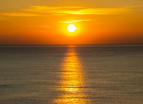 Stunning golden sunset over the Ligurian Sea with a vibrant orange sky, reflecting on calm waters.