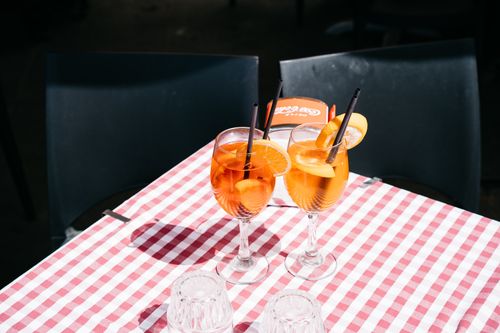 Free Two Aperol Spritz cocktails on a checkered tablecloth outdoors in the sun. Stock Photo