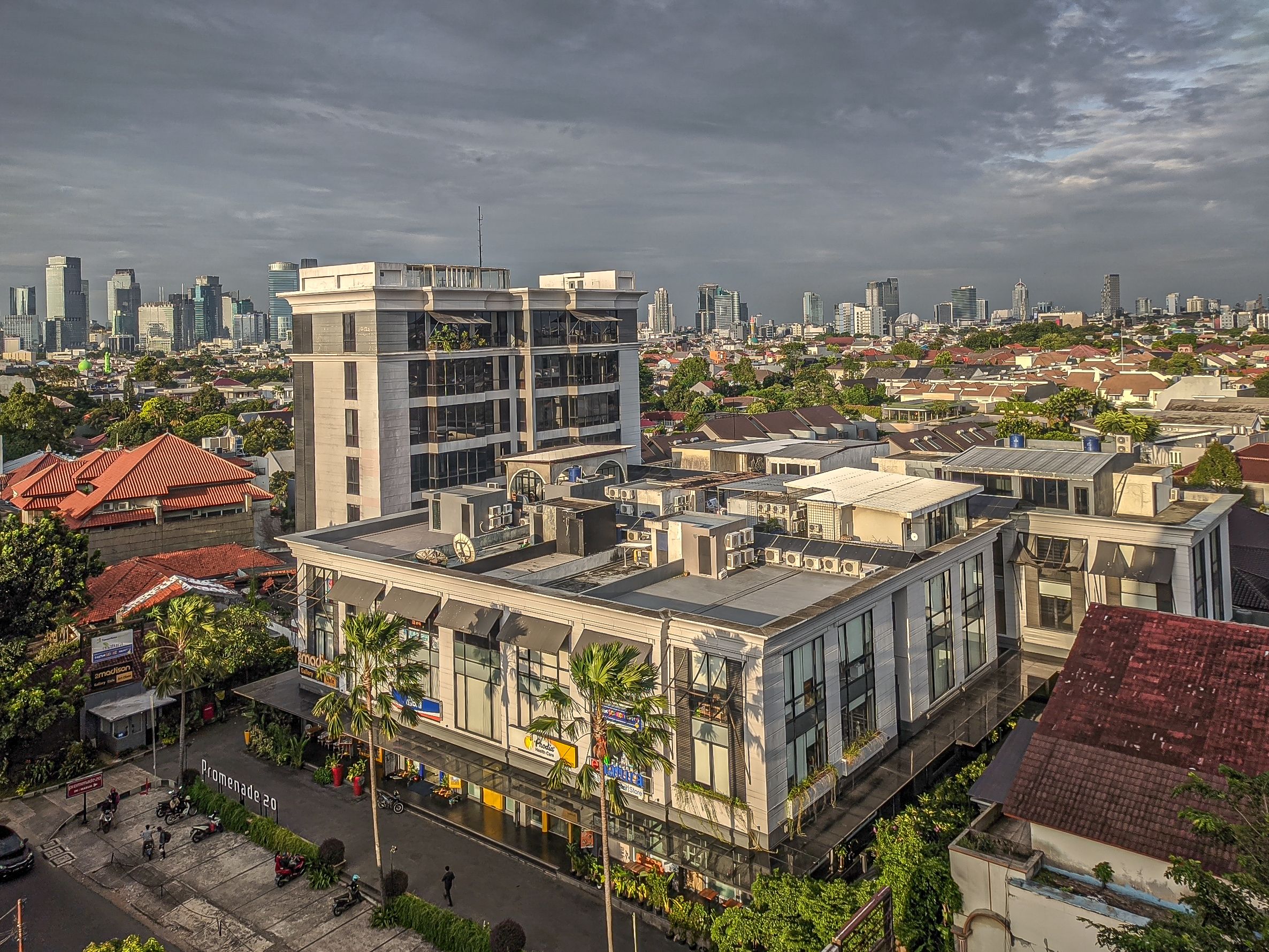 Aerial cityscape showcasing Jakarta's skyline and diverse architecture under a cloudy sky.