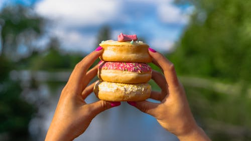 A Person's Hands Holding Donuts