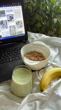 A cozy breakfast scene featuring a banana, cereal bowl, and laptop, ideal for remote work vibes.