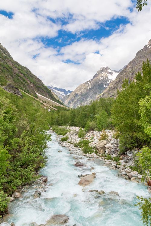 Free Flowing stream through lush valley and snowy peaks, Saint-Christophe-en-Oisans, France. Stock Photo