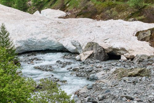 Free Scenic mountain stream flowing under snow in La Chapelle-en-Valgaudémar, French Alps. Stock Photo