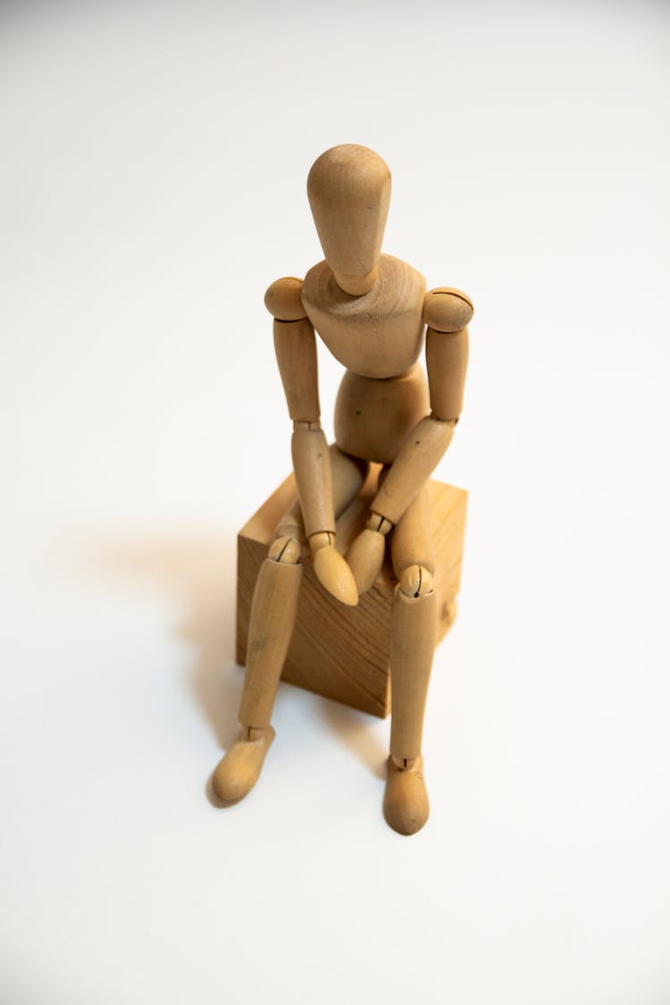 Wooden Human Figurine Sitting On Wooden Block