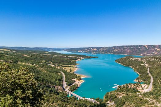 A breathtaking aerial shot of striking blue lake amidst lush greenery in Moustiers-Sainte-Marie, France.