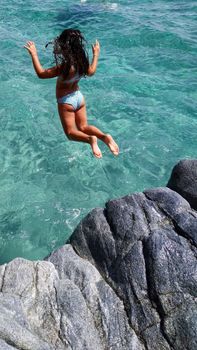 Woman in Blue Bikini Standing on Rock in Water
