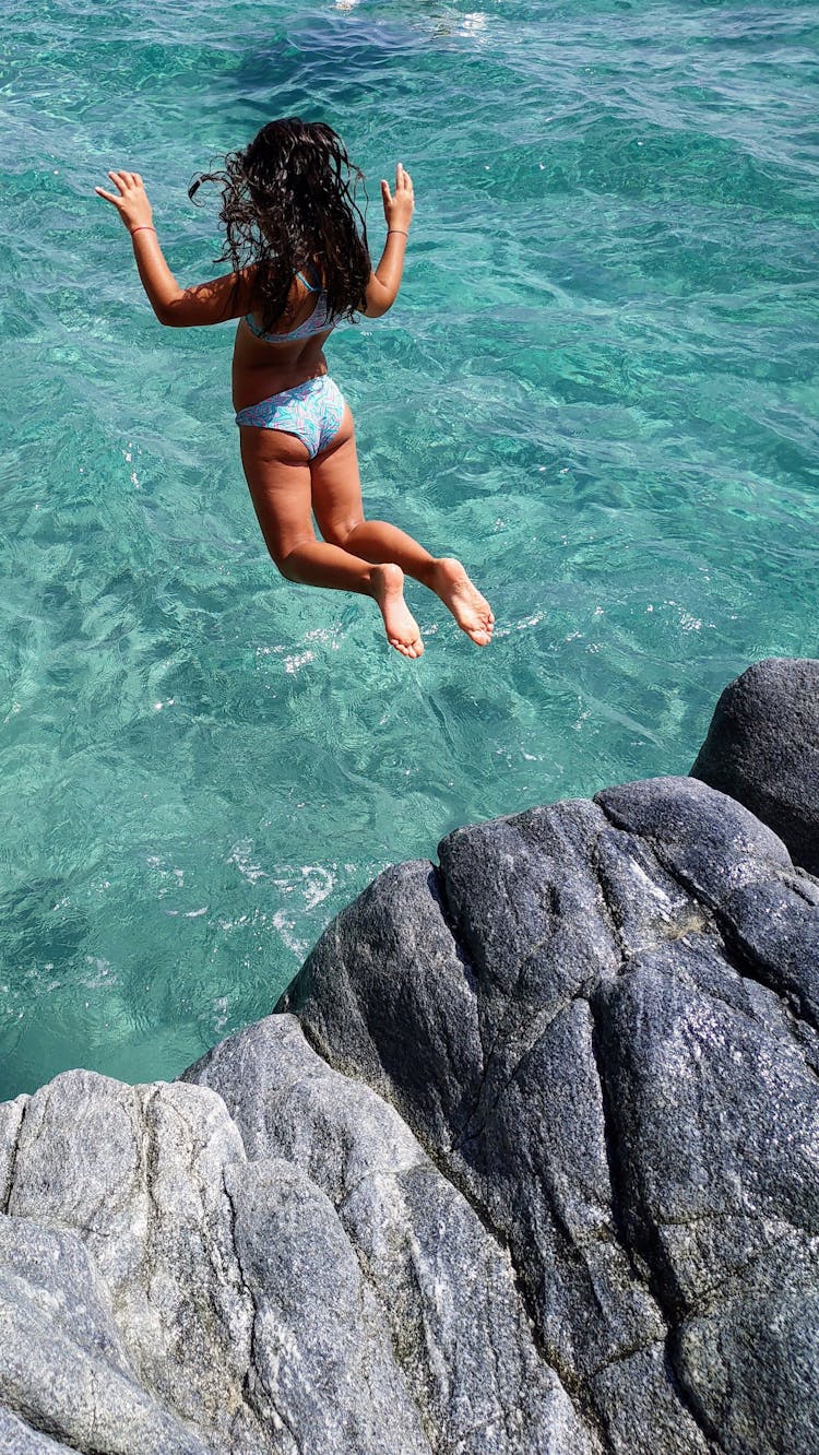 Woman In A Blue Bikini Jumping Off A Cliff