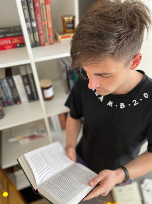 Teenage Boy Holding and Reading a Book