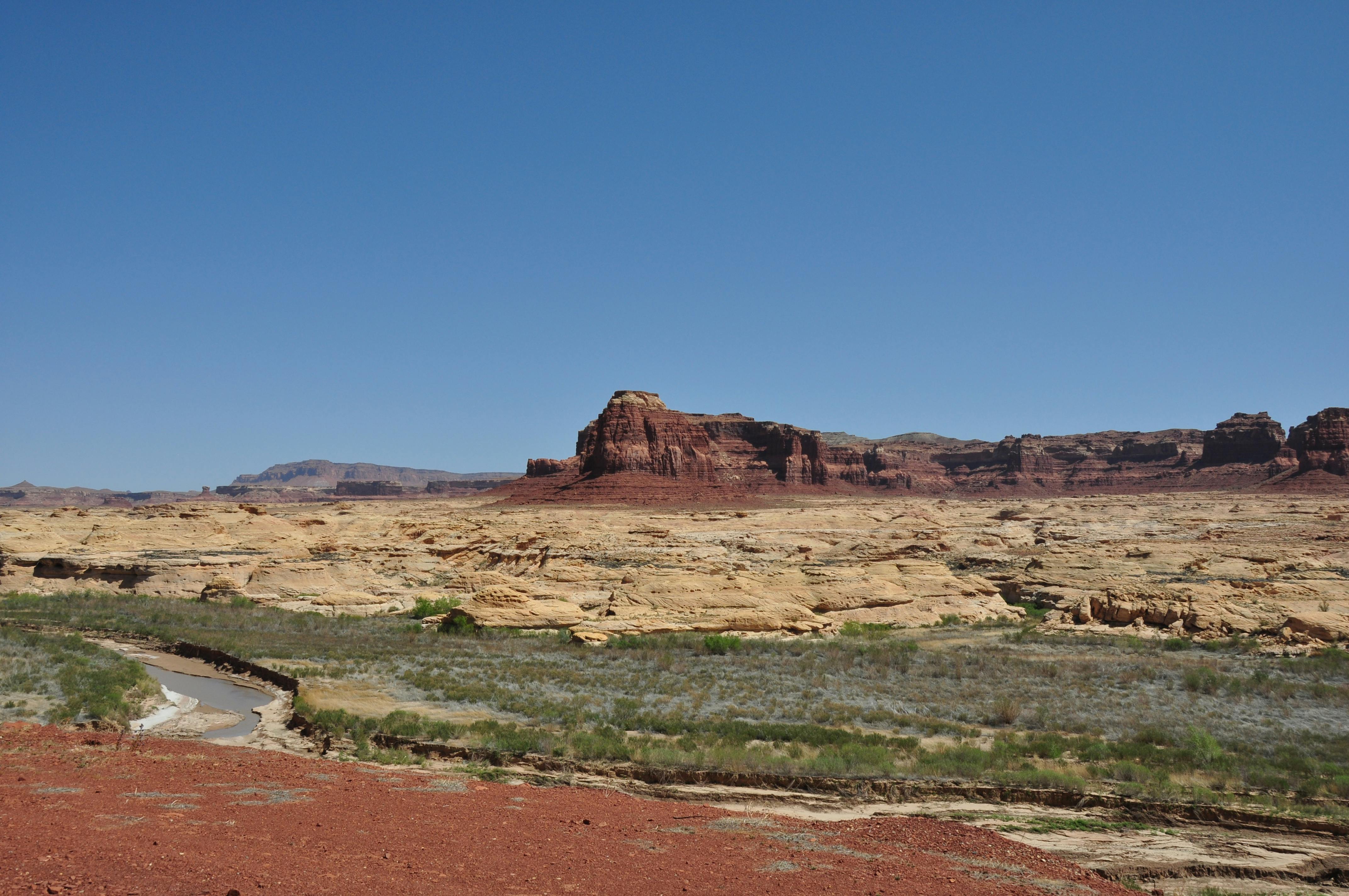 Stunning view of sandstone formations under a clear blue sky in Lake Powell, Utah.