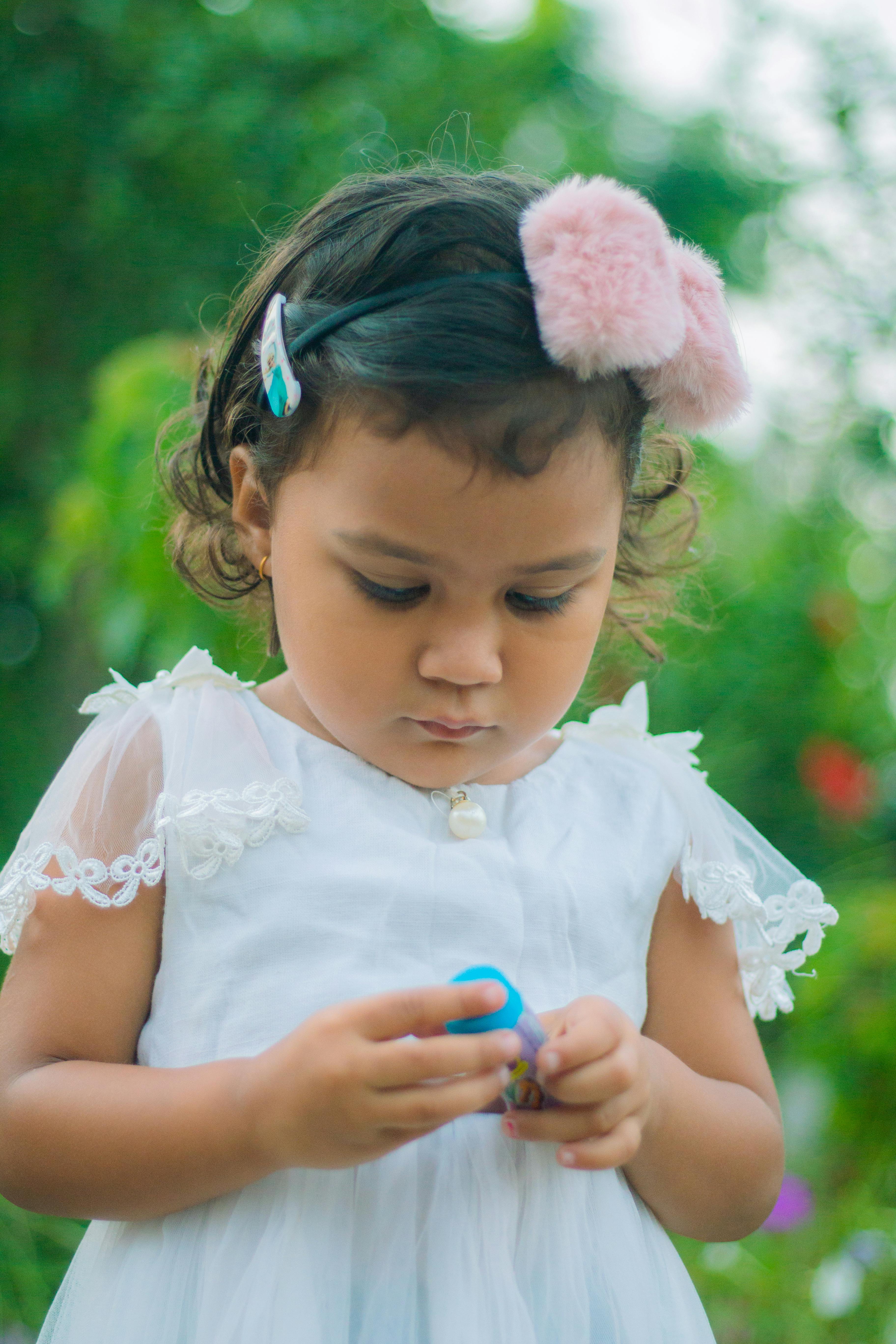 a young girl in white dress with pink headband