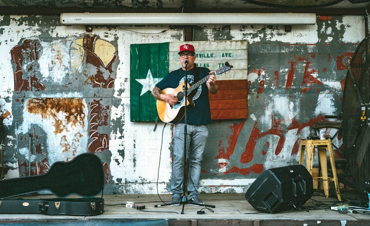 A Man Singing On The Street While Playing Guitar