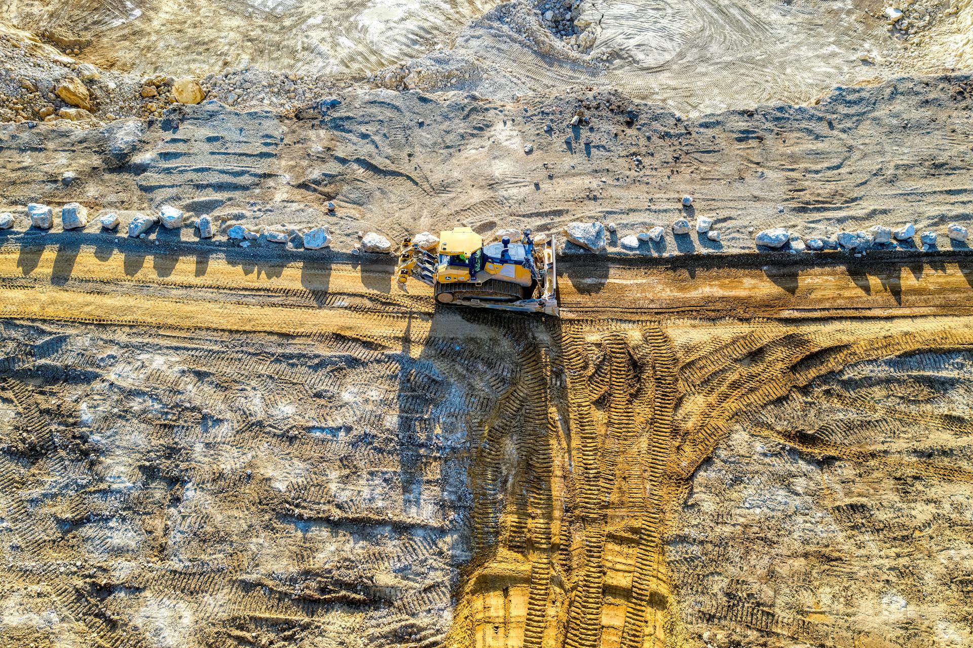 Aerial shot of bulldozer in action at a sandy construction site.