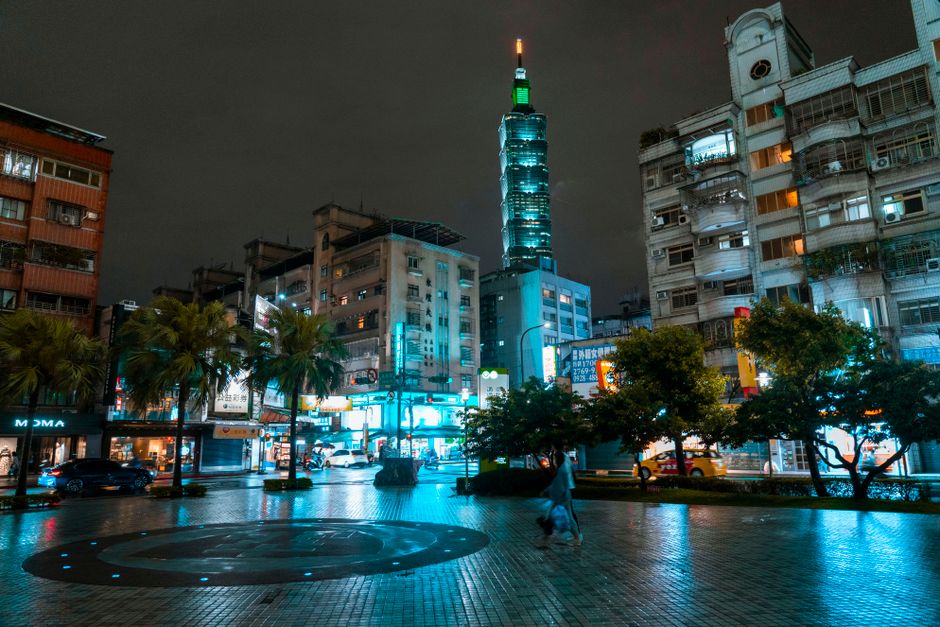 A person holding a compact umbrella on a rainy street in Taipei, Taiwan