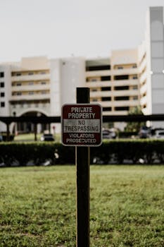 Vertical shot of a private property sign indicating no trespassing, with buildings visible in the background.