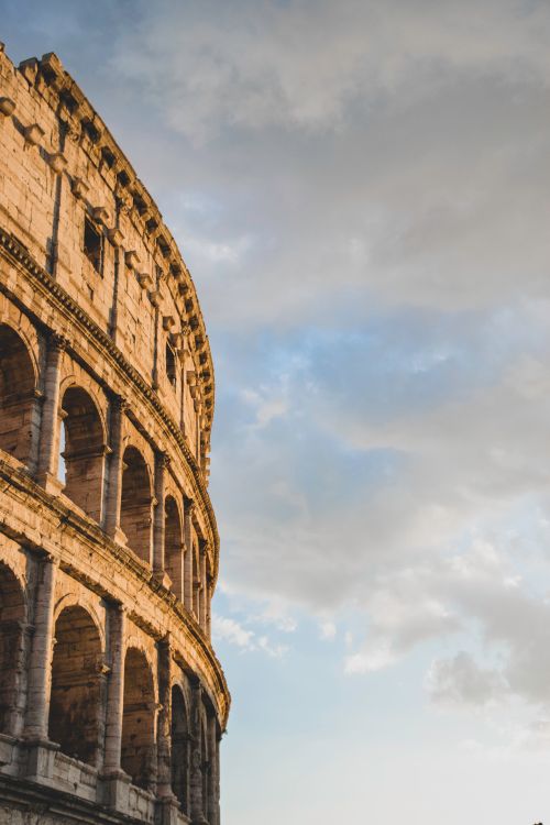 Free View of Rome's Colosseum with a dramatic cloudy sky, showcasing timeless architecture. Stock Photo