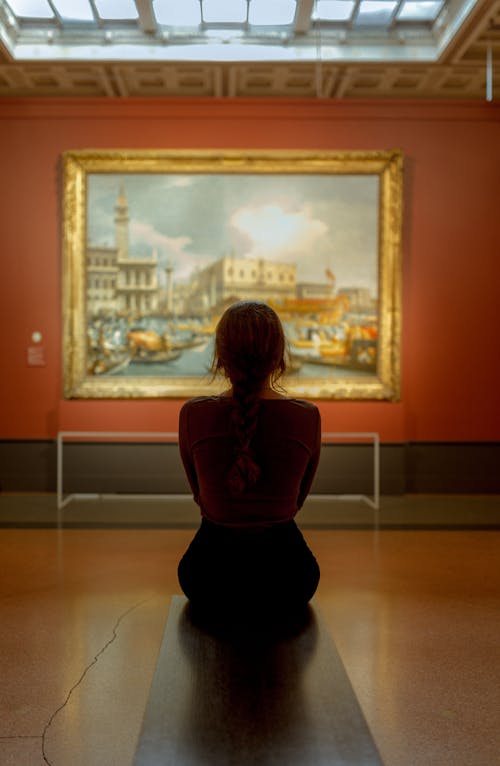 Woman Sitting in Front of a Wall Painting on an Orange Wall