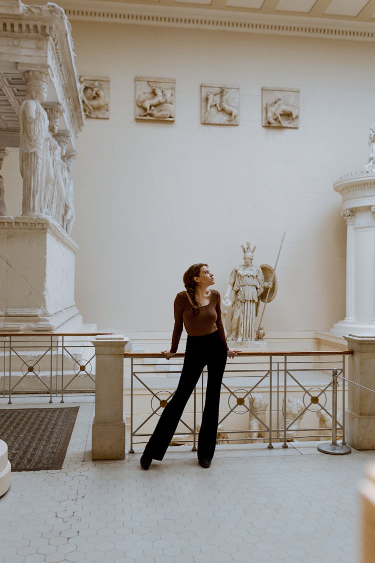 Photo Of A Standing Woman Leaning On Handrail In A Museum