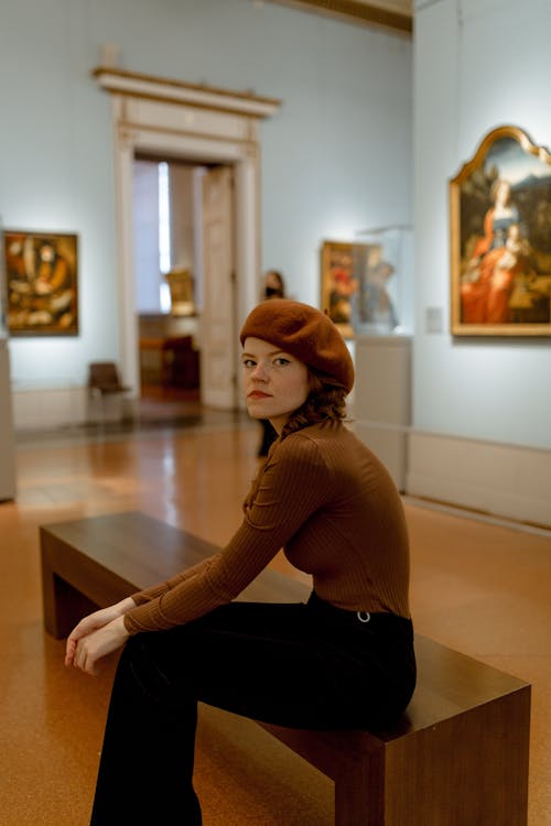 Free Portrait of a Young Woman Sitting in an Art Museum Stock Photo